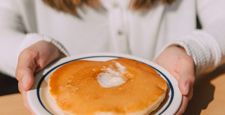 person holding a plate of pancake