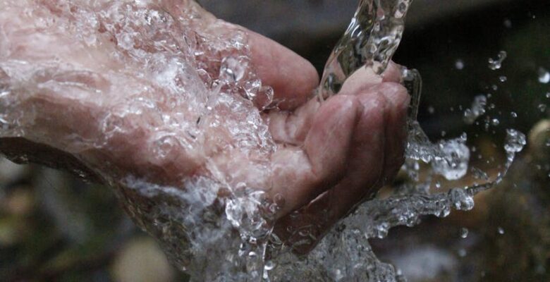 person cleaning hands under water