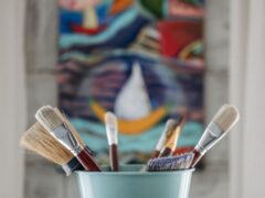 assorted paint brushes in a teal bucket