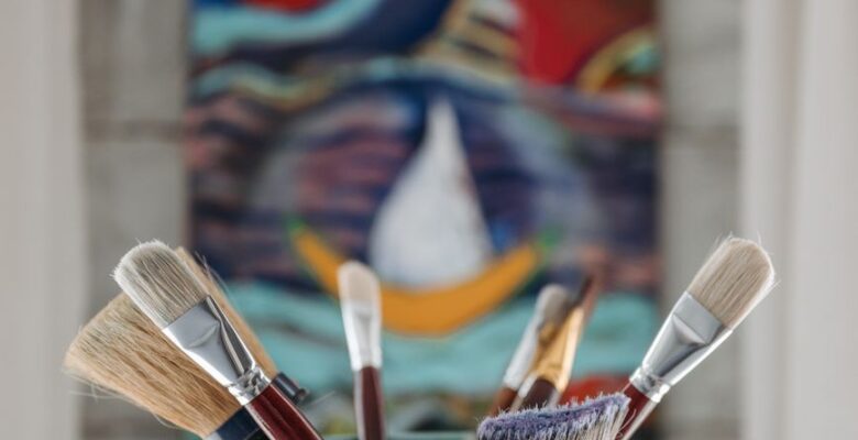 assorted paint brushes in a teal bucket